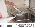 Cleaning a kitchen sink with a handheld steam cleaner during a home cleaning session 140078581