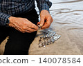 Man preparing medication on a soft surface at home during the afternoon 140078584
