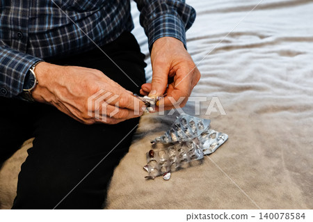 Man preparing medication on a soft surface at home during the afternoon Man preparing medication on a soft surface at home during the afternoon 140078584