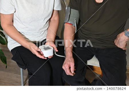Elderly man measures blood pressure of elderly woman at home Elderly man measures blood pressure of elderly woman at home 140078624