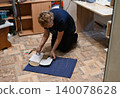 Person creates patterns on fabric with scissors on floor in home setting during daytime 140078628