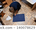 Person creates patterns on fabric with scissors on floor in home setting during daytime 140078629
