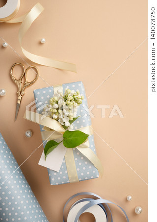 Gift box in light blue polka dot paper with cream satin ribbon, white lilac flowers, blank tag, gold scissors and pearls on beige background. Copyspace Gift box in light blue polka dot paper with cream satin ribbon, white lilac flowers, blank tag, gold scissors and pearls on beige background. Copyspace 140078750