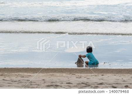 Young child building sandcastle sandy beach near gentle ocean waves Family vacation moment outdoor play coastal scenery Young child building sandcastle sandy beach near gentle ocean waves Family vacation moment outdoor play coastal scenery 140079468