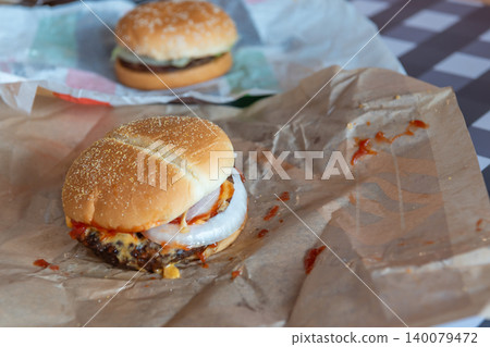 Juicy cheeseburger onion spicy sauce served paper wrap Fast food meal table shallow depth of field blurred burger background Juicy cheeseburger onion spicy sauce served paper wrap Fast food meal table shallow depth of field blurred burger background 140079472
