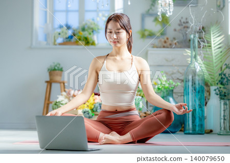 A young woman doing yoga online 140079650