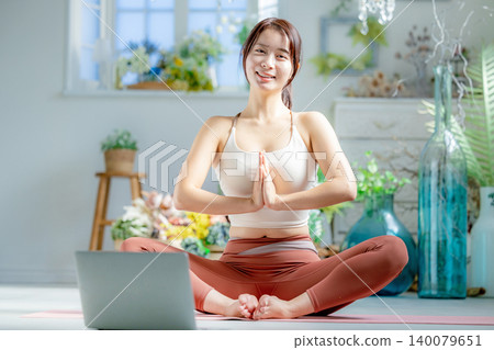 A young woman doing yoga online A young woman doing yoga online 140079651