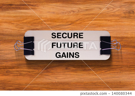 Secure Future Gains tagline written on wooden stick hold by binder clip with wooden texture background, business and investment, stock market theme Secure Future Gains tagline written on wooden stick hold by binder clip with wooden texture background, business and investment, stock market theme 140080344