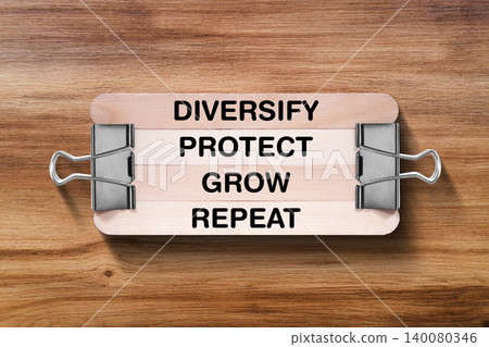 Diversify Protect Grow Repeat tagline written on wooden stick hold by binder clip with wooden texture background, business and investment, stock market theme 140080346