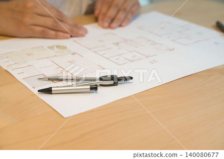 A hand writing on a design drawing with a pen A hand writing on a design drawing with a pen 140080677