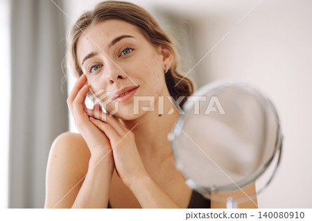 Young woman with problem skin looking into mirror. Inflammation on face, problem skin. Beauty care. Young woman with problem skin looking into mirror. Inflammation on face, problem skin. Beauty care. 140080910