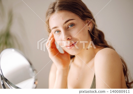 Young woman with problem skin looking into mirror. Inflammation on face, problem skin. Beauty care. 140080911