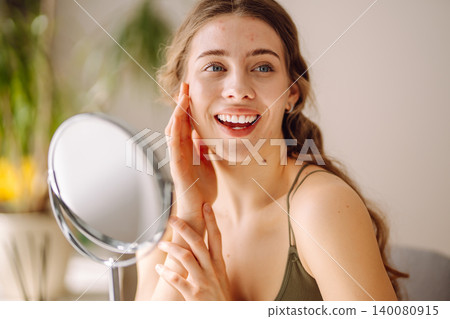 Young woman with problem skin looking into mirror. Inflammation on face, problem skin. Beauty care. Young woman with problem skin looking into mirror. Inflammation on face, problem skin. Beauty care. 140080915