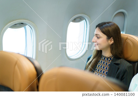 Woman passenger looking out window during airplane flight Woman passenger looking out window during airplane flight 140081100