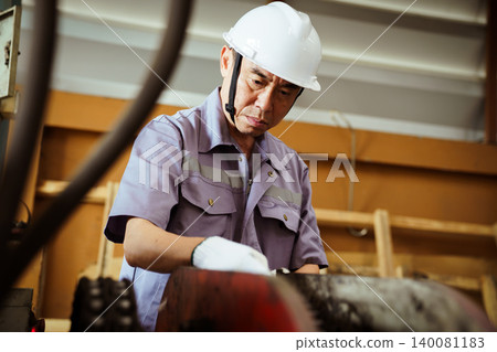 Senior Asian engineer inspecting machinery in factory. 140081183