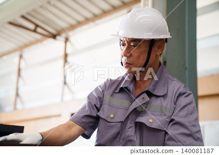 Senior Asian engineer inspecting machinery in factory. Senior Asian engineer inspecting machinery in factory. 140081187