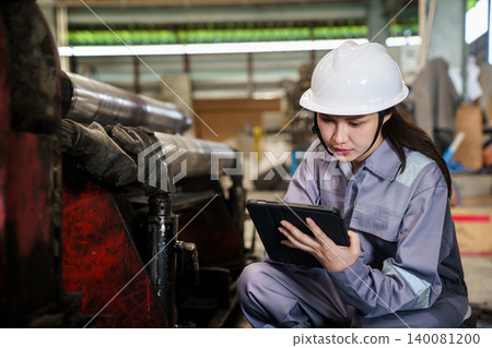 Woman technician checking machinery with digital tablet. Woman technician checking machinery with digital tablet. 140081200