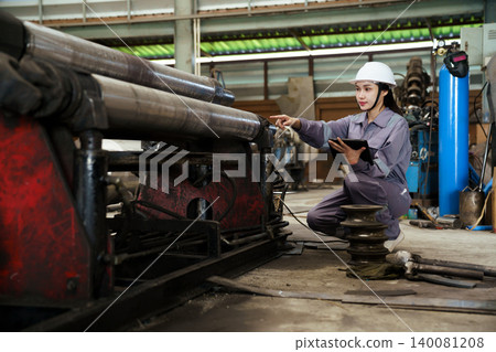 Female industrial worker in hardhat at manufacturing plant. Female industrial worker in hardhat at manufacturing plant. 140081208