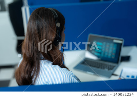 Friendly smiling female call-center agent with headset working on support hotline in office. Friendly smiling female call-center agent with headset working on support hotline in office. 140081224