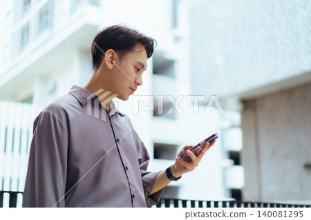 Asian businessman using smartphone standing outside office building Asian businessman using smartphone standing outside office building 140081295