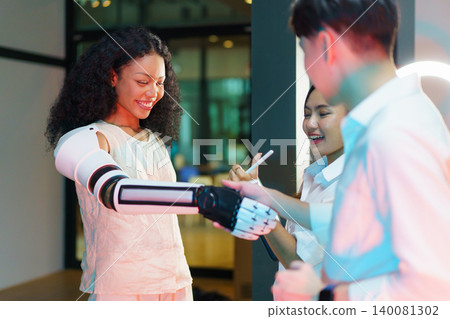 Asian engineering students testing robotic prosthetic arm in lab 140081302