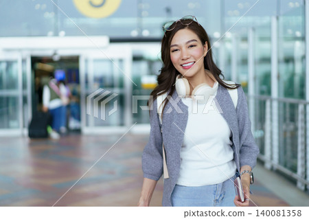 Happy Asian woman walking with suitcase at airport arrival 140081358