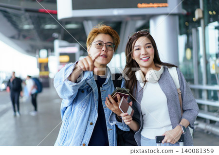 Two Asian female travelers finding direction at airport terminal Two Asian female travelers finding direction at airport terminal 140081359