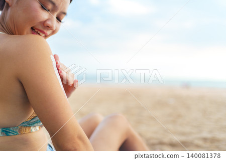 Asian woman applying sunscreen on shoulder at the beach 140081378