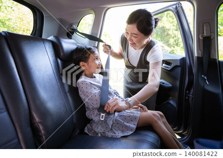 Asian mother fastening seat belt for her daughter in car Asian mother fastening seat belt for her daughter in car 140081422