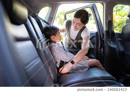 Asian mother fastening seat belt for her daughter in car Asian mother fastening seat belt for her daughter in car 140081423