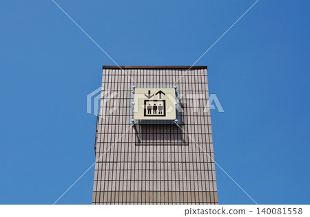 The pictogram of the outdoor elevator stands out against the clear blue sky. 140081558