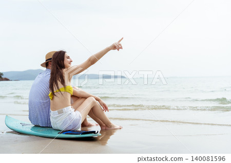 Young Couple Sitting on Surfboard Watching the Ocean at Beach Young Couple Sitting on Surfboard Watching the Ocean at Beach 140081596