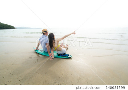 Young Couple Sitting on Surfboard Watching the Ocean at Beach 140081599