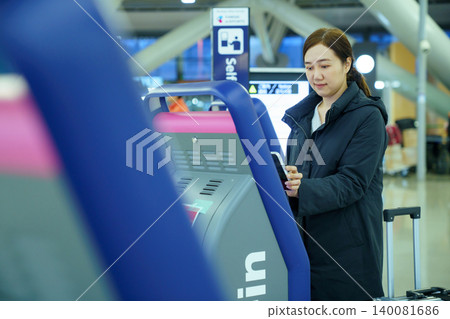 Asian Woman Checking In at Airport Self Service Kios. 140081686