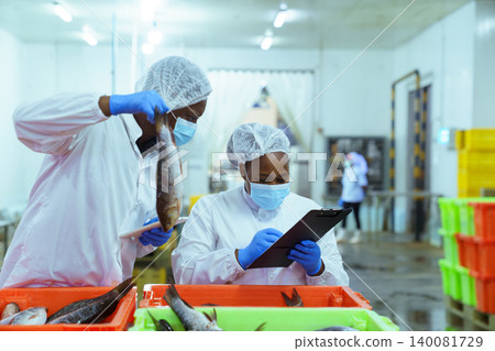 Quality Control Workers Inspecting Fresh Fish in Seafood Processing Plant Quality Control Workers Inspecting Fresh Fish in Seafood Processing Plant 140081729