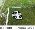 Deflated soccer ball on green grass field near the goal post, failure or missed opportunity concept 140081851