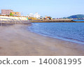 A photograph of the beach near a hot spring bath with steam rising in the early morning. 140081995