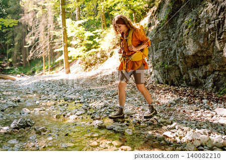 Traveler walks along forest hiking trail in mountains against the backdrop of mountain nature. Traveler walks along forest hiking trail in mountains against the backdrop of mountain nature. 140082210