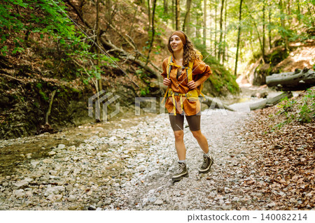 A traveler walks along forest hiking trail in mountains on a sunny day. Outdoor recreation concept. A traveler walks along forest hiking trail in mountains on a sunny day. Outdoor recreation concept. 140082214