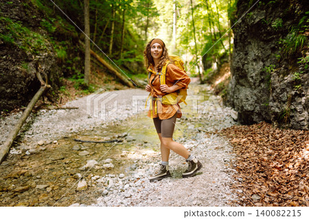 A traveler walks along forest hiking trail in mountains on a sunny day. Outdoor recreation concept. A traveler walks along forest hiking trail in mountains on a sunny day. Outdoor recreation concept. 140082215