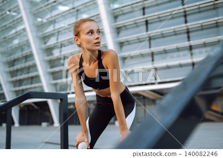 Young woman in sports outfit doing exercises outdoors in morning. Sports training, healthy lifestyle Young woman in sports outfit doing exercises outdoors in morning. Sports training, healthy lifestyle 140082246