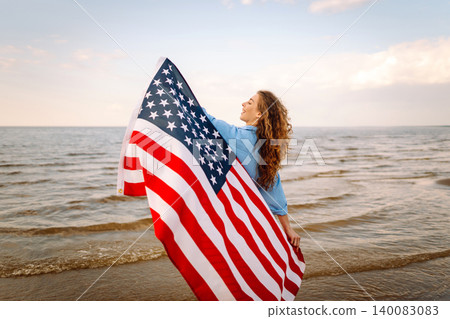 Young woman with American flag on beach. Patriotic holiday. Independence Day concept 140083083