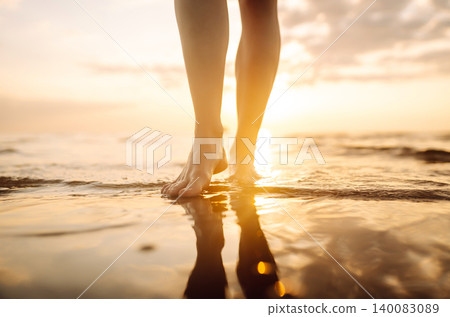 Close-up young woman's legs walking on wave of sea water and sand on beach. Concept of vacation. Close-up young woman's legs walking on wave of sea water and sand on beach. Concept of vacation. 140083089