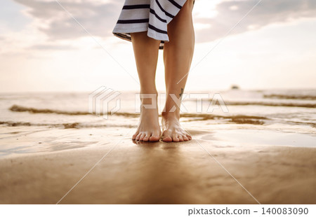 Close-up young woman's legs walking on wave of sea water and sand on beach. Concept of vacation. 140083090