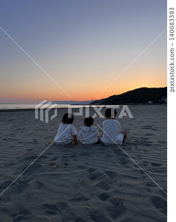The backs of three brothers sitting on the beach, watching the sunset. The backs of three brothers sitting on the beach, watching the sunset. 140083393