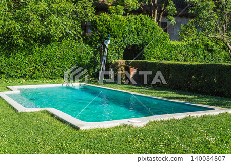Swimming pool with crystal clear water in landscaped Mediterranean garden near traditional countryside residence 140084807