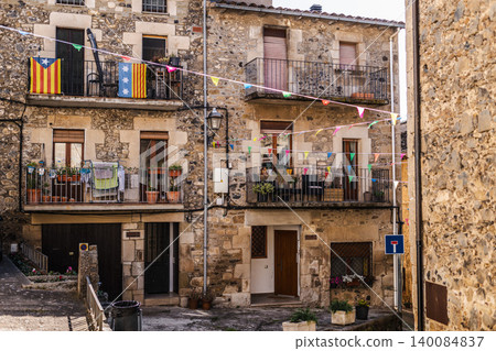 Traditional stone houses with balconies and colorful festival decorations in historic Catalan village square Traditional stone houses with balconies and colorful festival decorations in historic Catalan village square 140084837