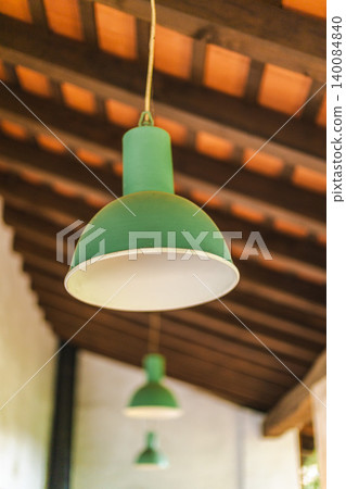 Vintage green pendant lamps hanging beneath wooden ceiling in rustic countryside interior 140084840