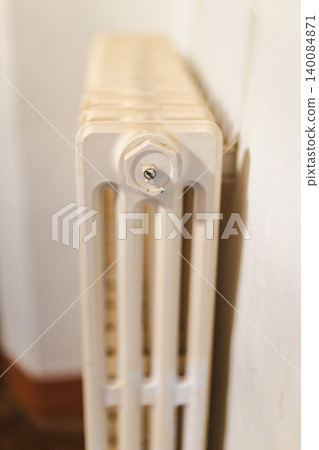 Close up view of vintage cast iron radiator with heating valve in traditional home interior Close up view of vintage cast iron radiator with heating valve in traditional home interior 140084871