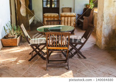 Traditional Mediterranean courtyard with wooden table and chairs in rustic country house Traditional Mediterranean courtyard with wooden table and chairs in rustic country house 140084880